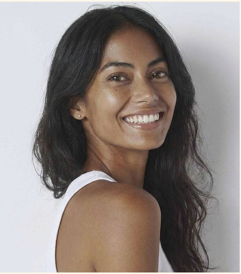 Smiling model glancing over her shoulder in a white tank